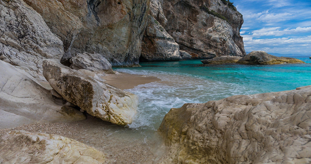 Une Crique rocheuse, un peu de sable avec une mer bleu azur.