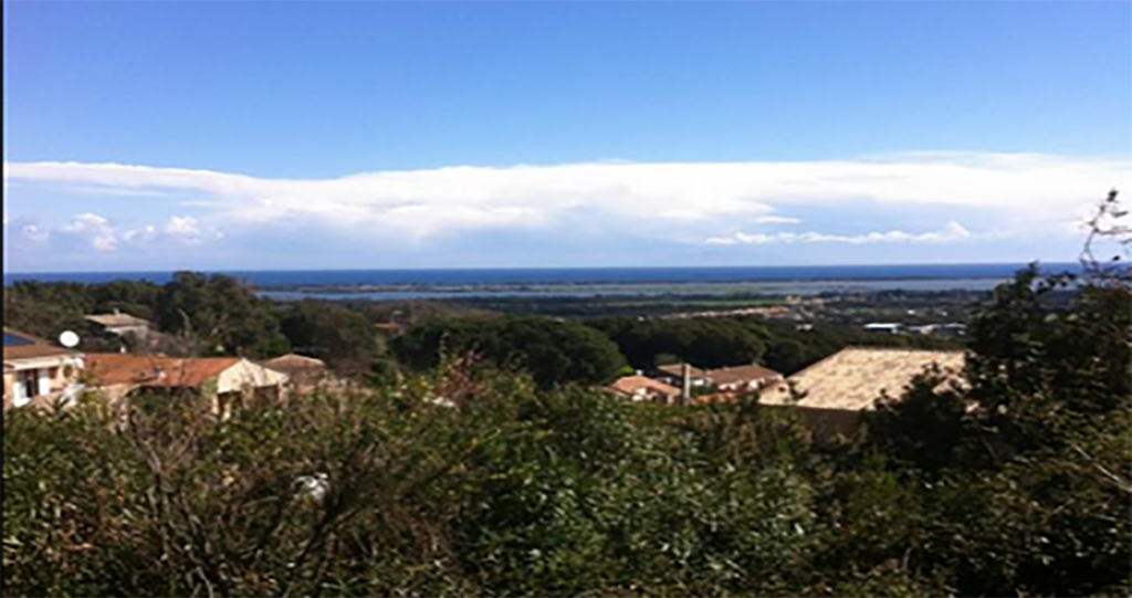 Vue sur la mer, derrière quelques maison au calme.